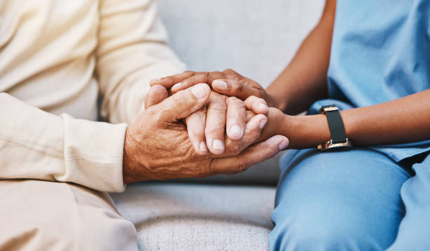 EMIC caregiver holding hands with a client — compassionate home care